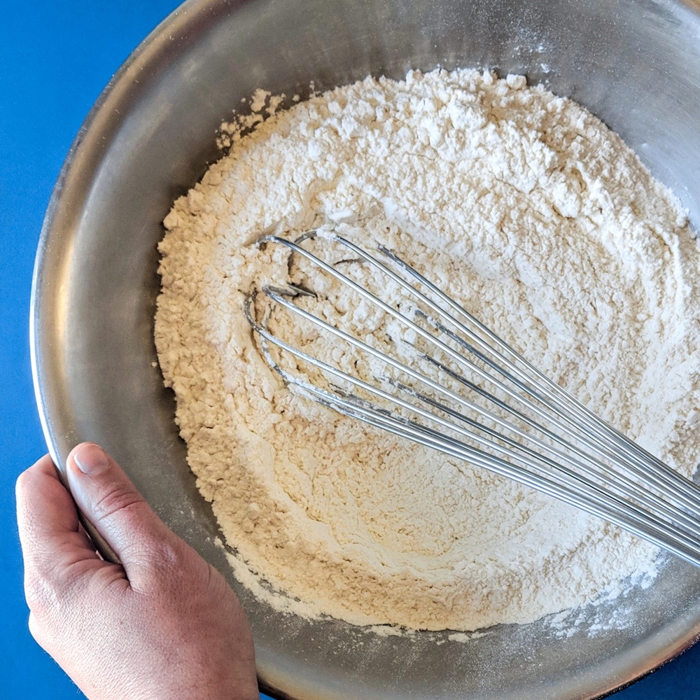 Hands whisking and combining dry ingredients for recipe