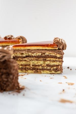 A side view of a slice of Dobos Torta on a marble surface.