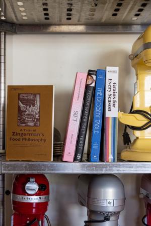 cookbooks on a shelf next to a yellow stand mixer