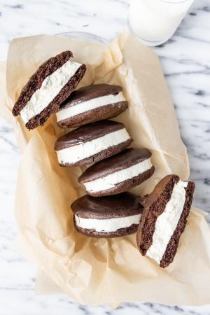 An overhead shot of Swiss Buttercream filled chocolate cake sandwiches covered in chocolate with a glass of milk 