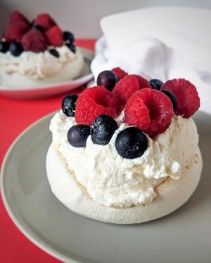 Pavlova topped with whipped cream and fresh berries