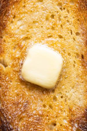 a close-up photo of a piece of sourdough toast with a melty pat of butter on top